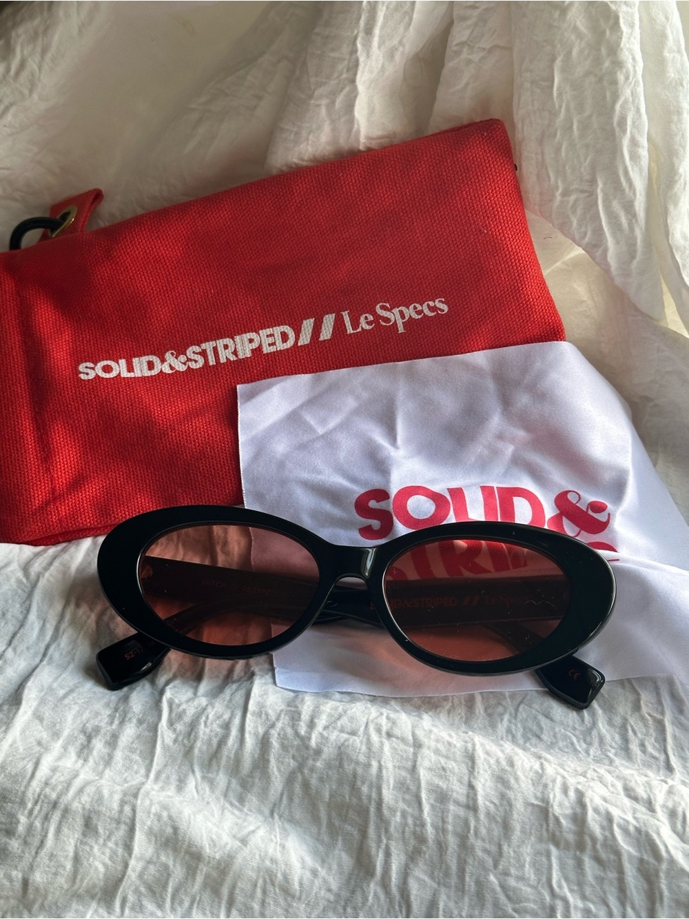 SOLID & STRIPED Black Oval Sunglasses with Red-Tinted Lenses
